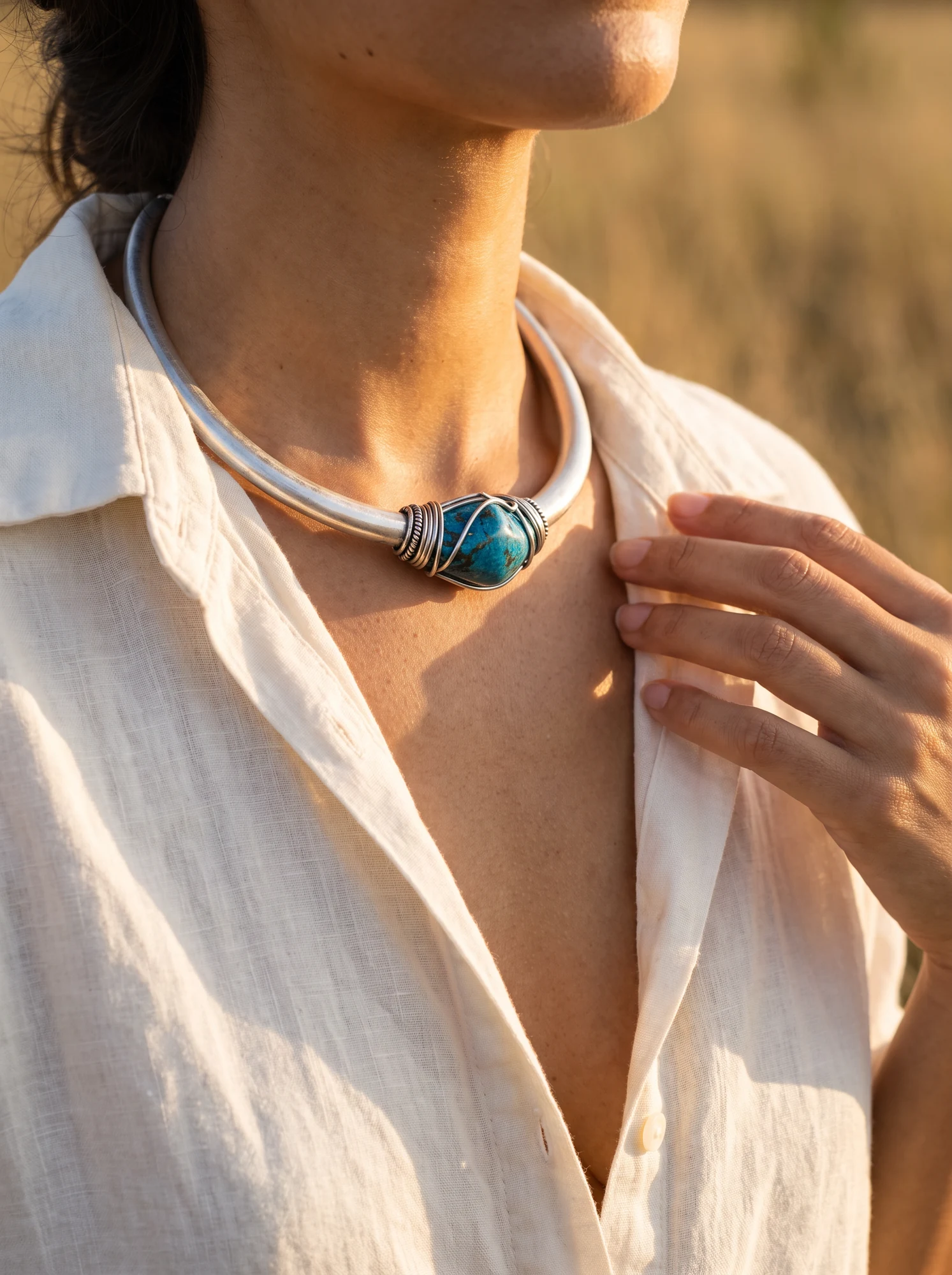 Detalhe de um colar azul usado com camisa de linho na luz do cerrado